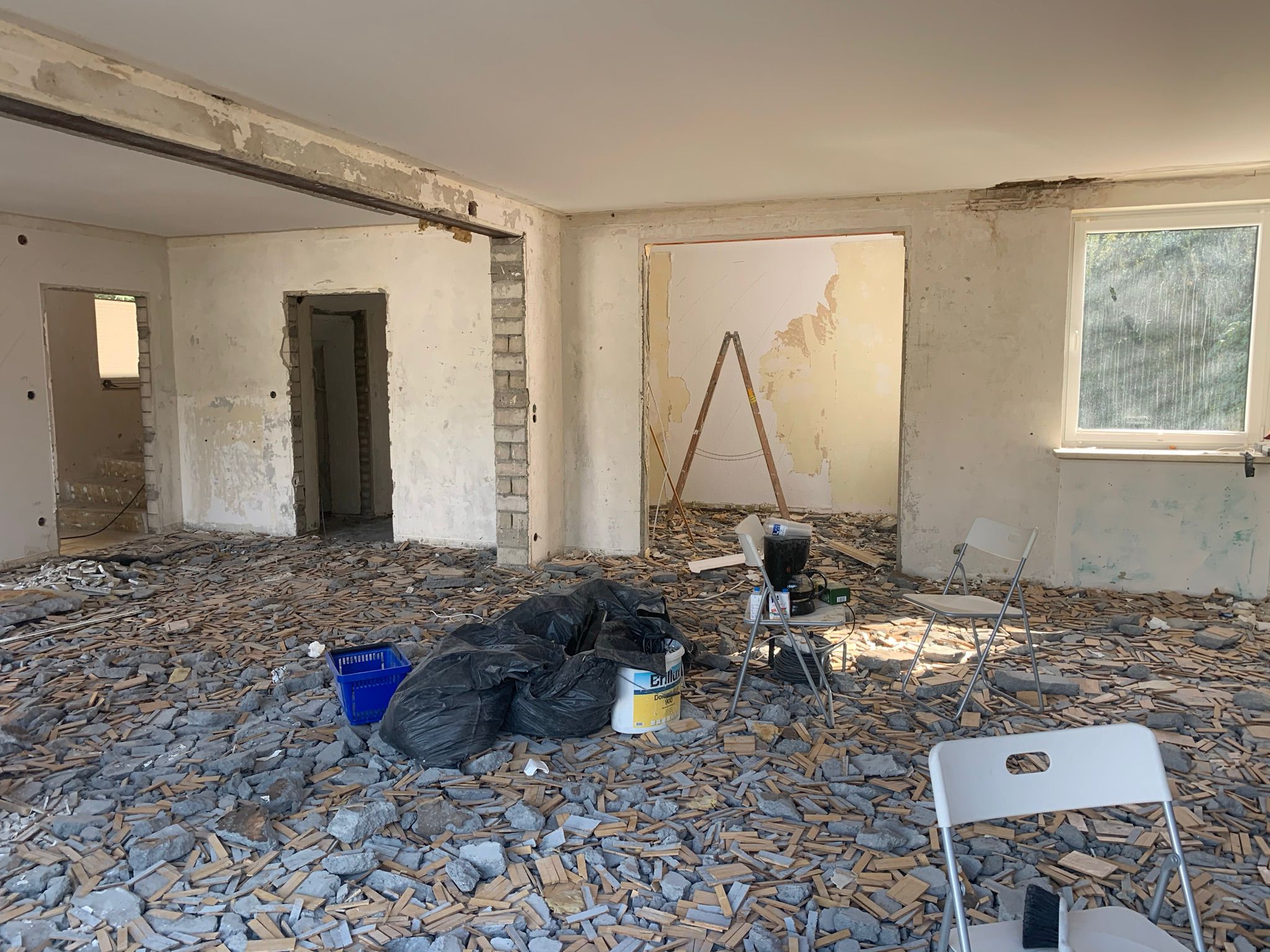 Sanierungsbedürftiger Raum mit beschädigter Decke, abblätternder Tapete und unebenem Holzboden, bereit für eine Komplettsanierung.